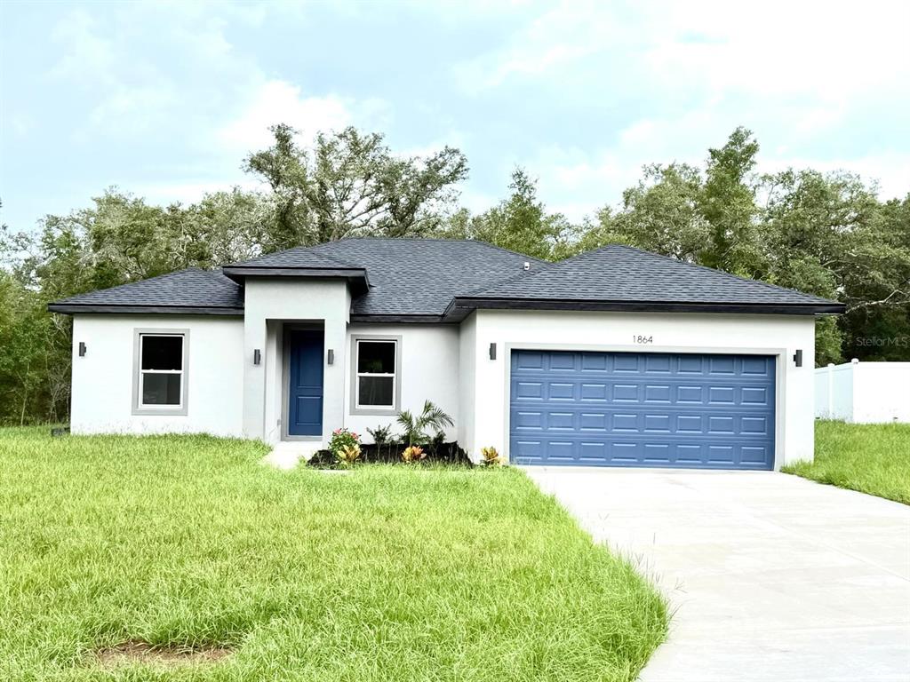 A single-story house with white stucco walls, a blue garage door, and a dark roof — 1864 W ROSEBORO DRIVE, CITRUS SPRINGS, FL
