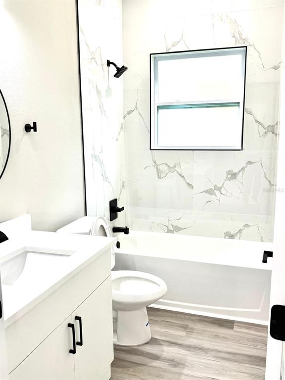 A bathroom features a white vanity, a toilet, and a tub with marble-look tile walls — 1864 W ROSEBORO DRIVE, CITRUS SPRINGS, FL
