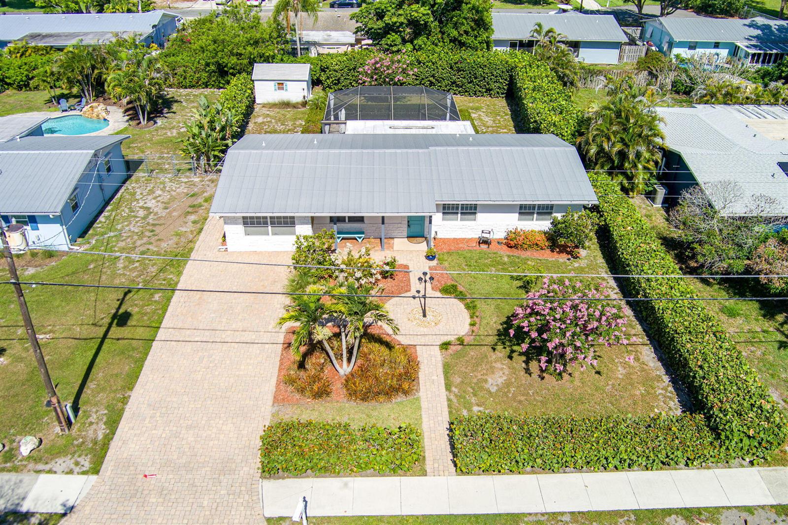 An aerial view shows a single-story house with a metal roof, driveway, and landscaped yard — 1252 SE Madison Avenue, Stuart FL 34996, STUART, FL