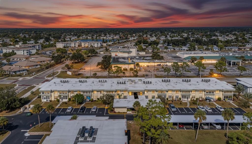 An aerial view shows a multi-story apartment building with a parking lot and surrounding neighborhood — 21267 GERTRUDE AVENUE UNIT 212, PORT CHARLOTTE, FL