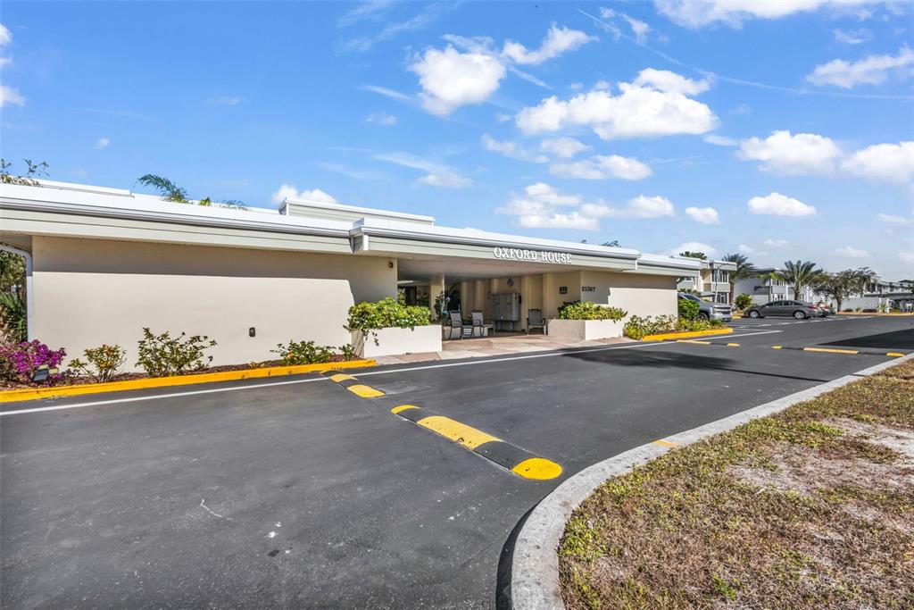 The exterior of a low-rise apartment building features a covered entrance labeled Oxford House — 21267 GERTRUDE AVENUE UNIT 212, PORT CHARLOTTE, FL