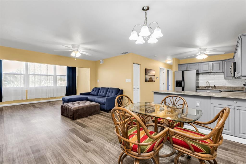 An open-concept living and dining area features wood-look flooring, a blue sofa, and a kitchen — 21267 GERTRUDE AVENUE UNIT 212, PORT CHARLOTTE, FL