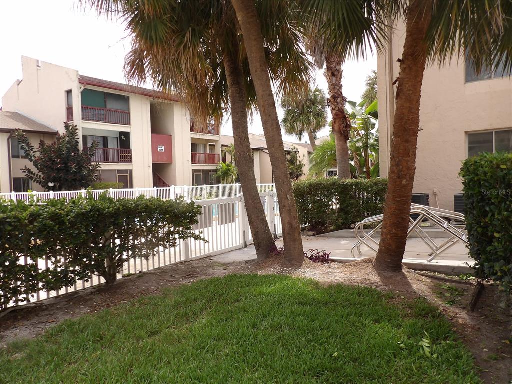 A grassy yard with palm trees and a white fence borders a swimming pool area — 3836 N LAKE DRIVE UNIT 119, TAMPA, FL
