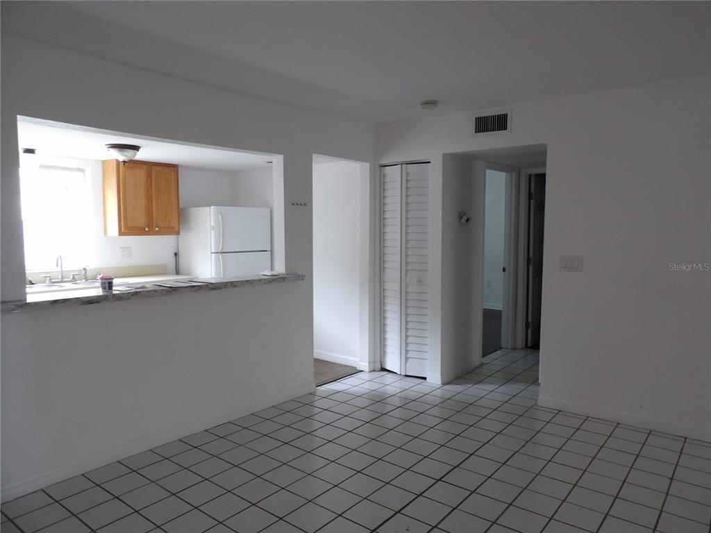 A room with white tiled floors, a kitchen pass-through window, and a hallway entrance — 3836 N LAKE DRIVE UNIT 119, TAMPA, FL