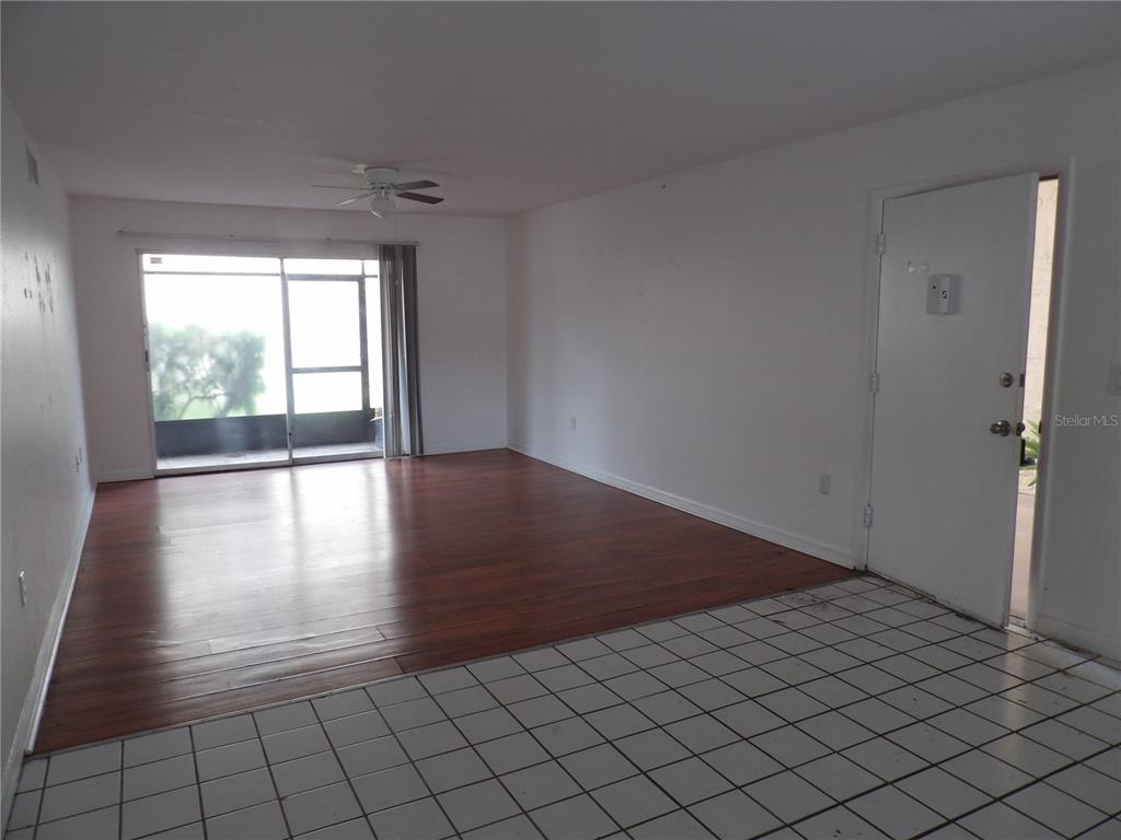 An open living area features wood-look flooring, white walls, a ceiling fan, and tiled entry — 3836 N LAKE DRIVE UNIT 119, TAMPA, FL