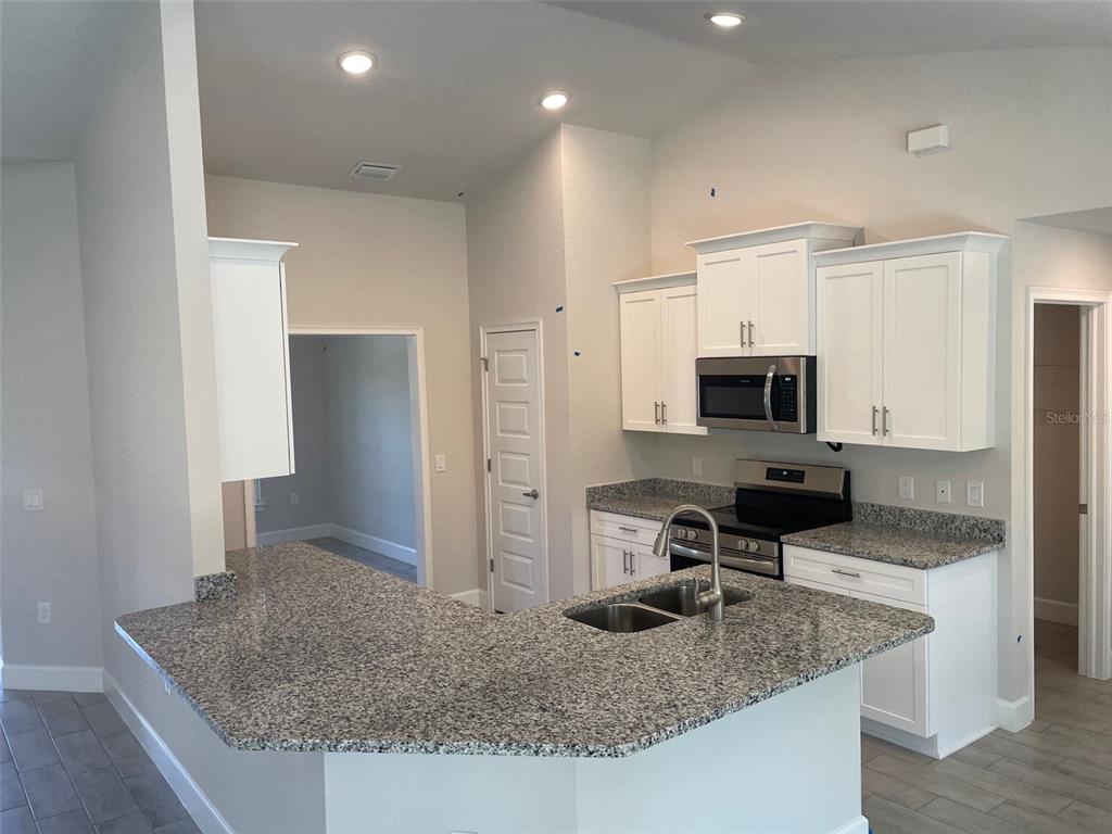 A kitchen features white cabinets, granite countertops, a stainless steel microwave, and a breakfast bar — 17433 EDGEWATER DRIVE, PORT CHARLOTTE, FL