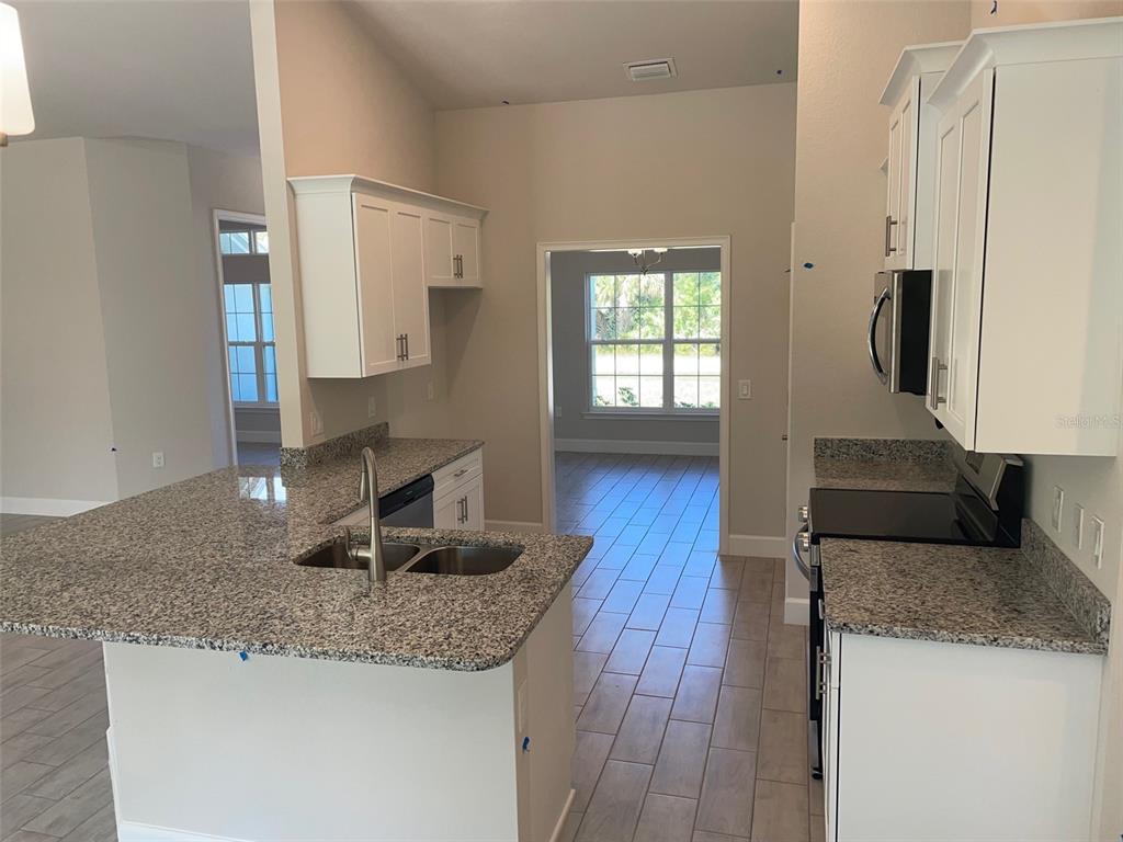 A kitchen with granite countertops, stainless steel appliances, and light-colored tile flooring — 17433 EDGEWATER DRIVE, PORT CHARLOTTE, FL