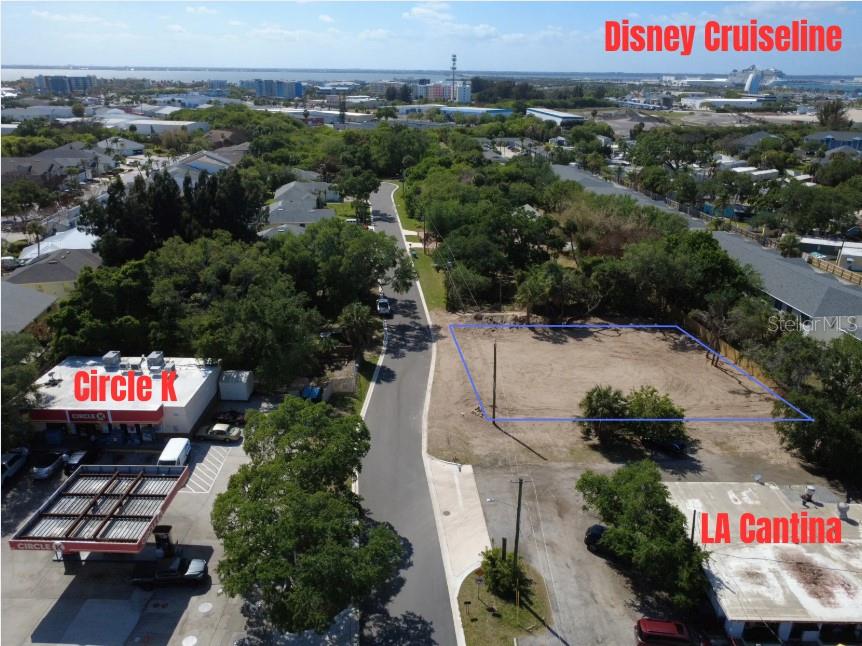 An aerial view shows a vacant lot outlined in blue next to a road and businesses — OAK LANE, CAPE CANAVERAL, FL