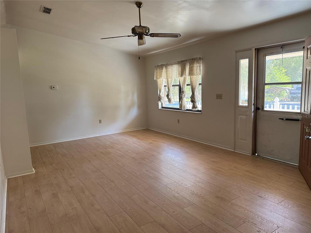 A living room features light wood-look flooring, a ceiling fan, and a front entry door — 9706 SW 30TH TERRACE, OCALA, FL