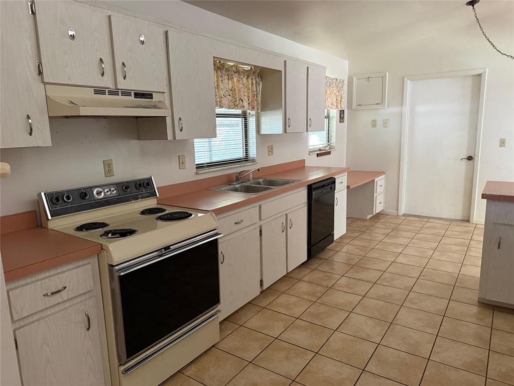 A kitchen features light wood cabinets, pink laminate countertops, a white stove, and tile flooring — 9706 SW 30TH TERRACE, OCALA, FL