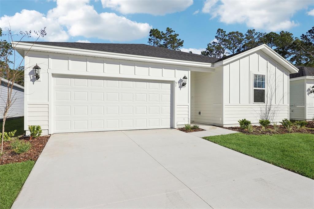 A white single-story house features vertical siding, a two-car garage, and a concrete driveway — 51 WANDERING CREEK WAY, PALM COAST, FL