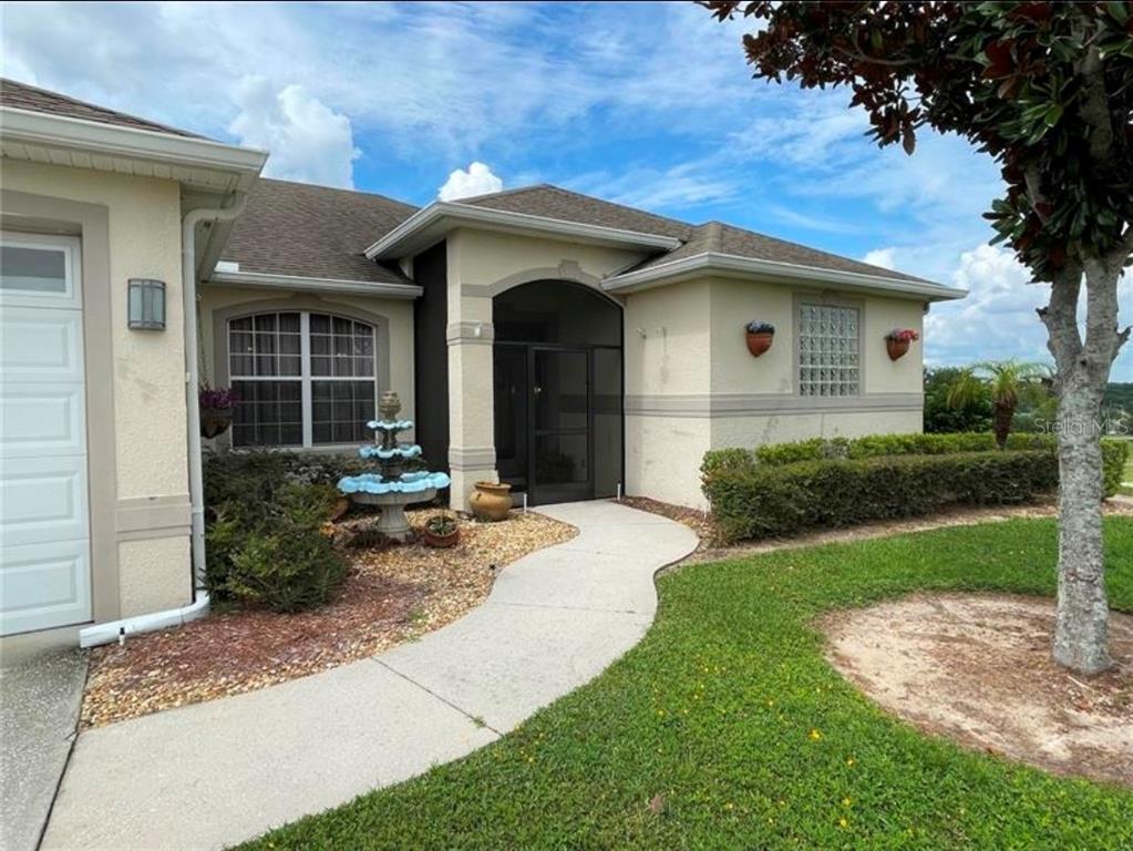 A tan stucco house features a screened entryway, a concrete walkway, and a tiered fountain — 2915 SOUTHERN PINES LOOP, CLERMONT, FL