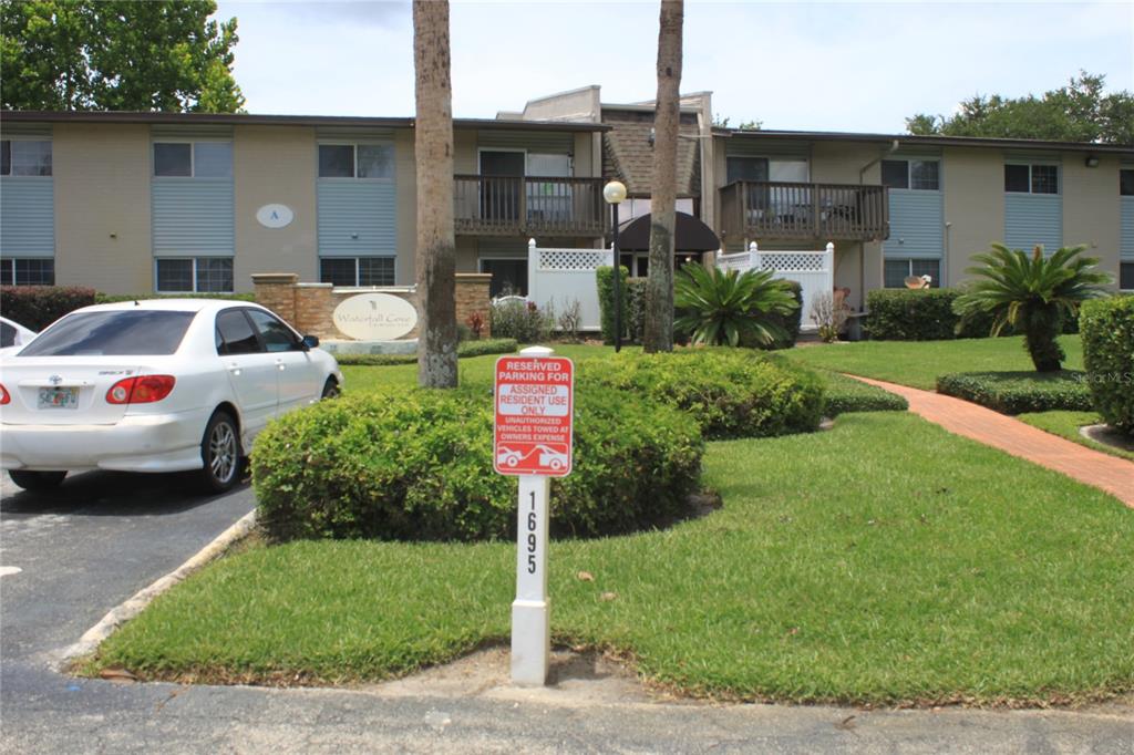 A white sedan is parked in front of a two-story apartment building with reserved parking — 1695 LEE ROAD UNIT A101, WINTER PARK, FL