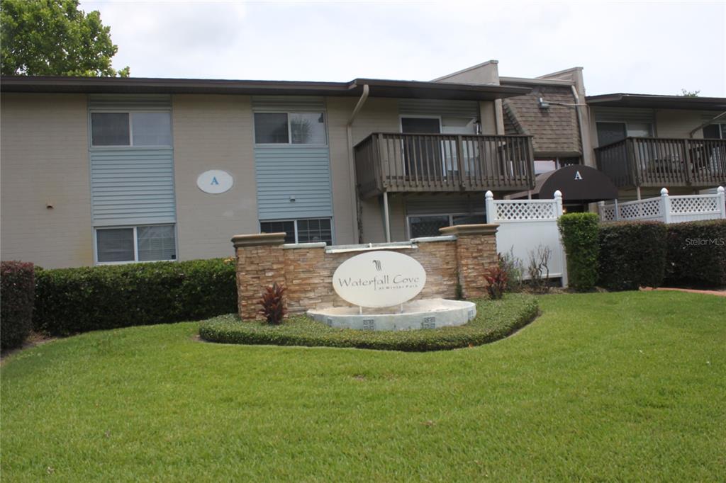 The exterior of a two-story apartment building features a stone monument sign for Waterfall Cove — 1695 LEE ROAD UNIT A101, WINTER PARK, FL