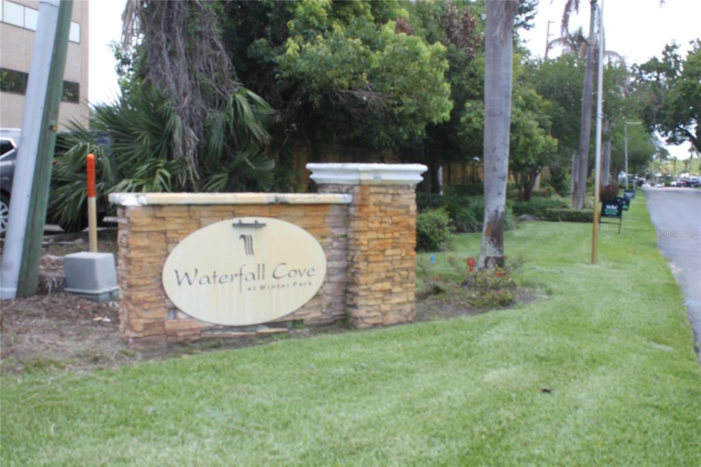 A stone monument sign for Waterfall Cove at Winter Park stands on a grassy lawn — 1695 LEE ROAD UNIT A101, WINTER PARK, FL