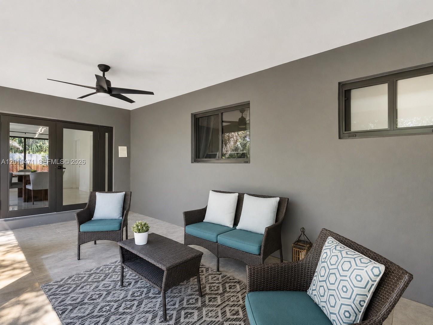 A covered patio features gray walls, wicker furniture with teal cushions, and a ceiling fan — 400 NW 30th Ct, Wilton Manors FL 33311, WILTON MANORS, FL