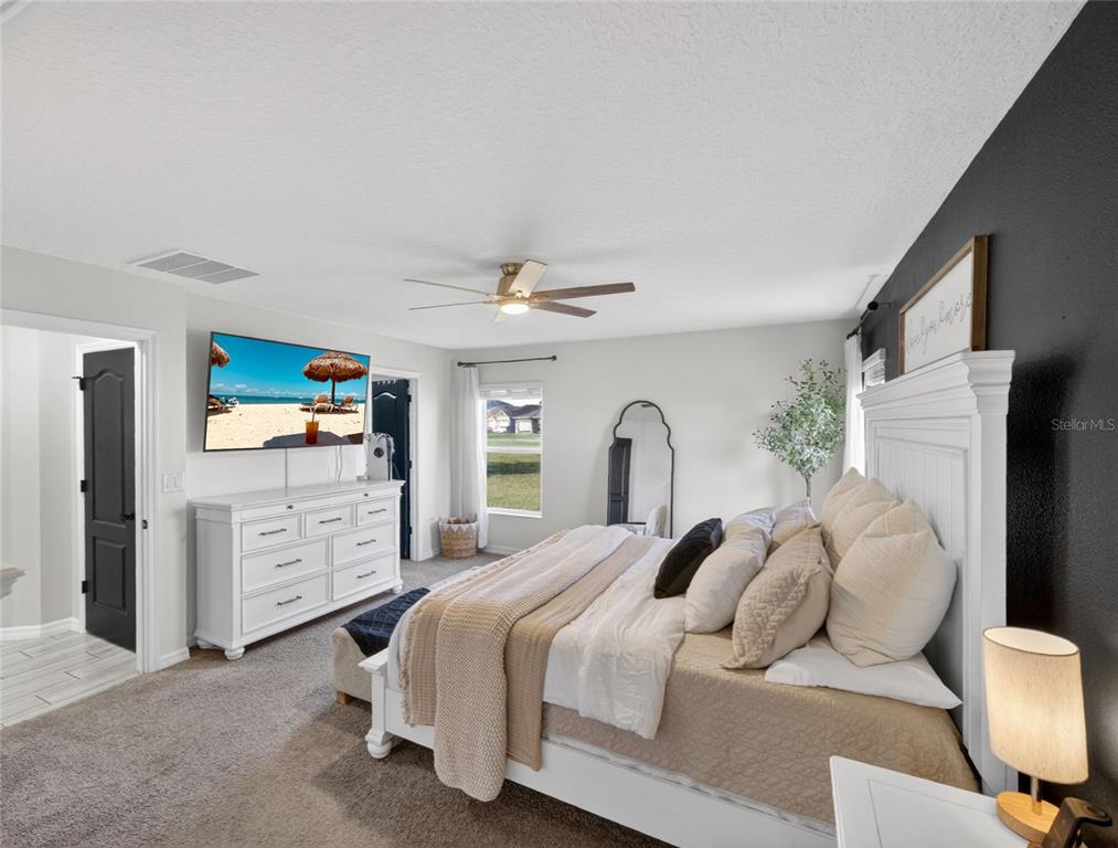 A bedroom features a white bed frame, a white dresser, and a black accent wall — 3109 LAKES CREST AVENUE, ST CLOUD, FL