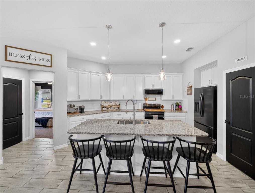 A kitchen with white cabinets, granite countertops, a central island, and black bar stools — 3109 LAKES CREST AVENUE, ST CLOUD, FL
