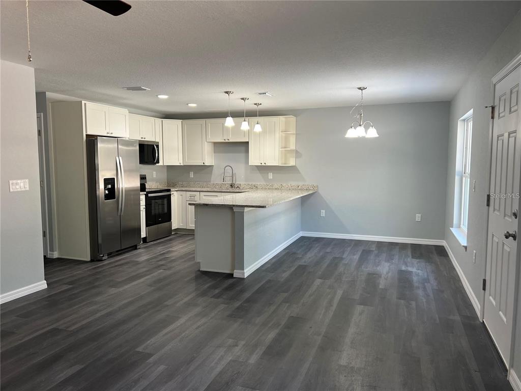 A kitchen with white cabinets, stainless steel appliances, and a granite-topped island — 2190 NW 65TH PLACE, OCALA, FL