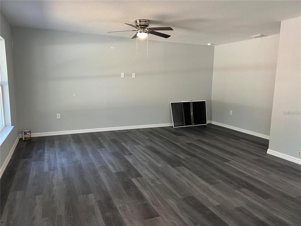 An empty room features gray walls, dark wood-look flooring, and a ceiling fan — 2190 NW 65TH PLACE, OCALA, FL