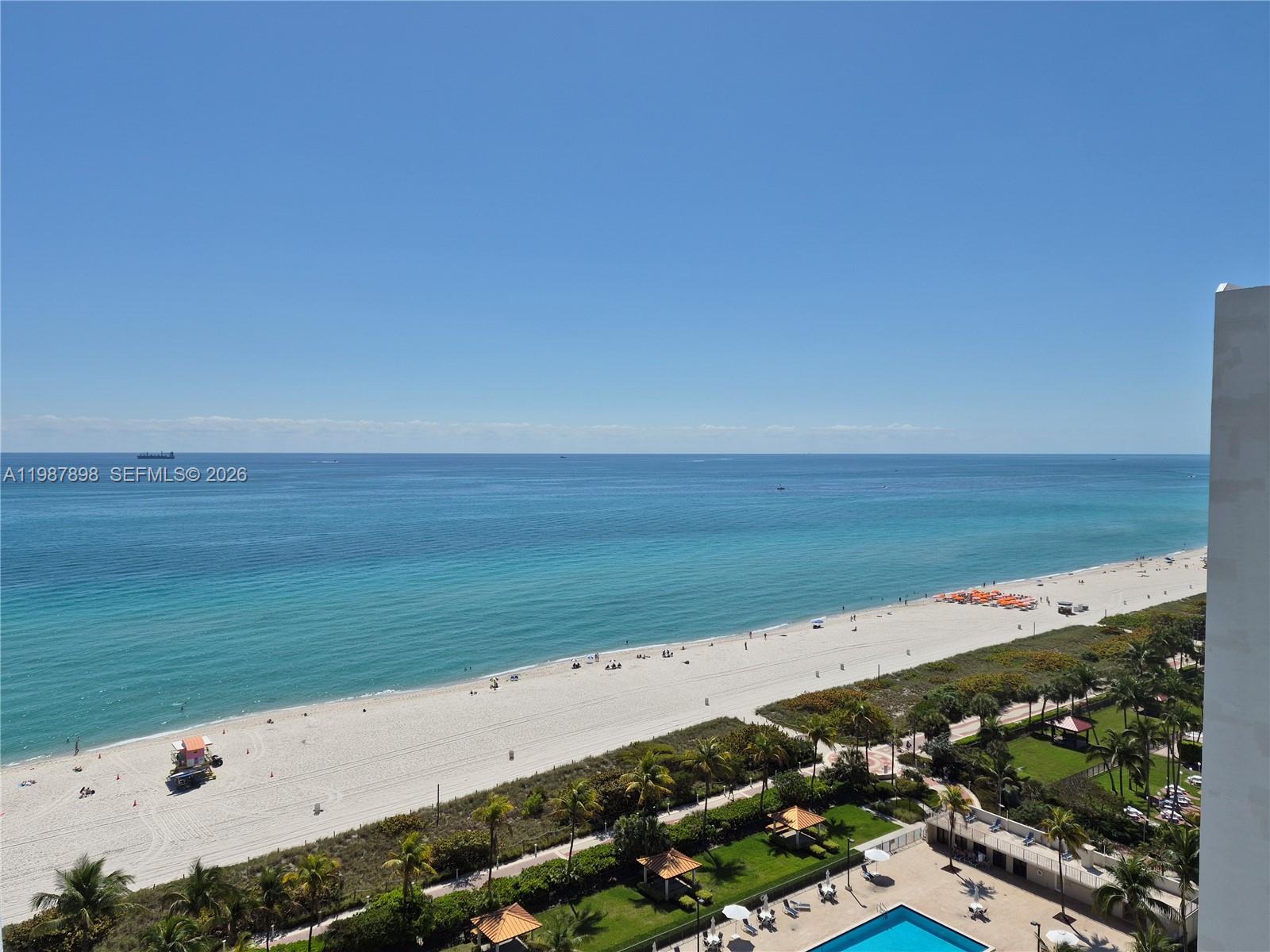 An elevated view of a sandy beach, turquoise ocean, and a resort pool area — 2655 Collins Ave # 1910, Miami Beach FL 33140, MIAMI BEACH, FL
