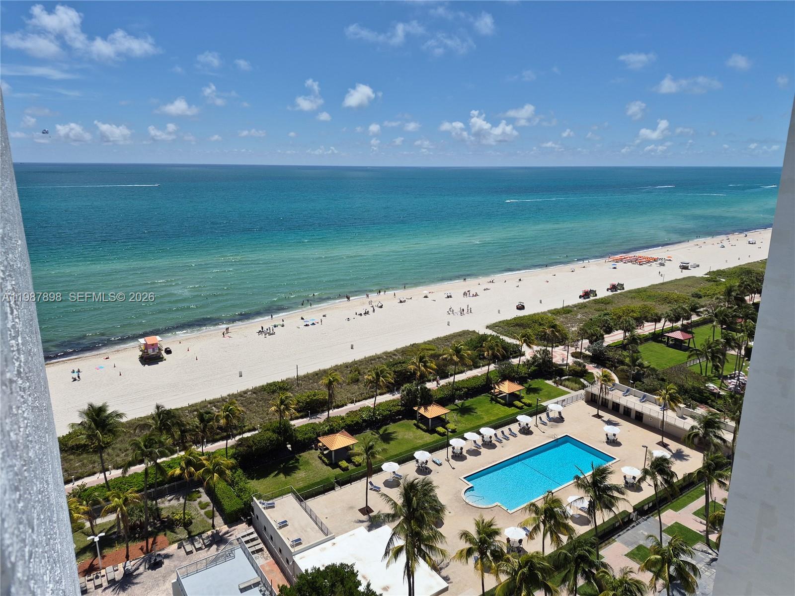 An elevated view shows a swimming pool, palm trees, and a sandy beach with ocean — 2655 Collins Ave # 1910, Miami Beach FL 33140, MIAMI BEACH, FL