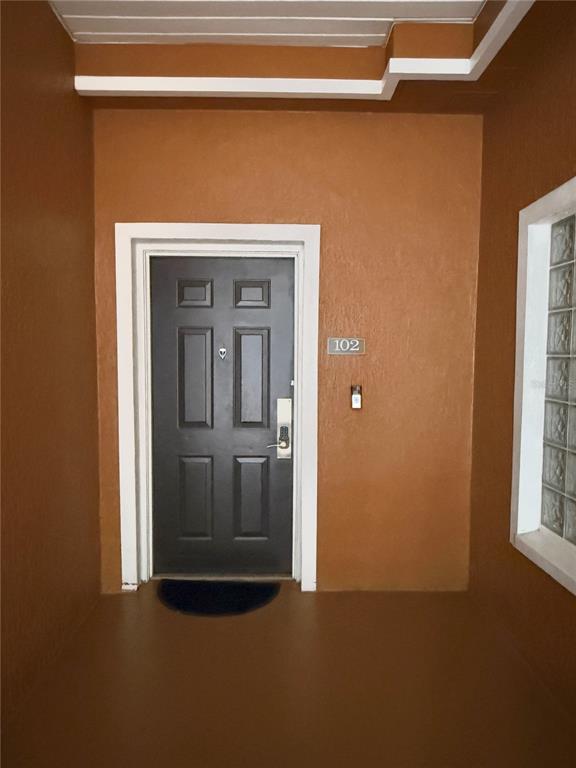 A dark brown front door with a keypad lock is set in a tan entryway — 3060 PIRATES RETREAT COURT UNIT 102, KISSIMMEE, FL