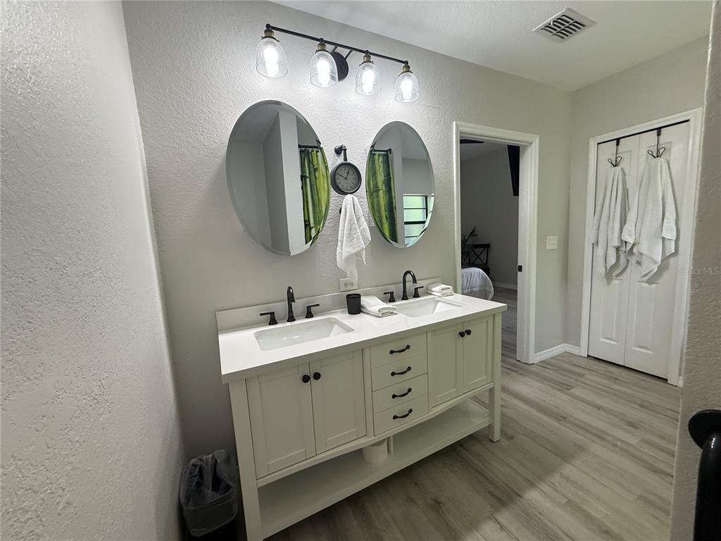A bathroom features a white double vanity with two oval mirrors and a light fixture — 3060 PIRATES RETREAT COURT UNIT 102, KISSIMMEE, FL
