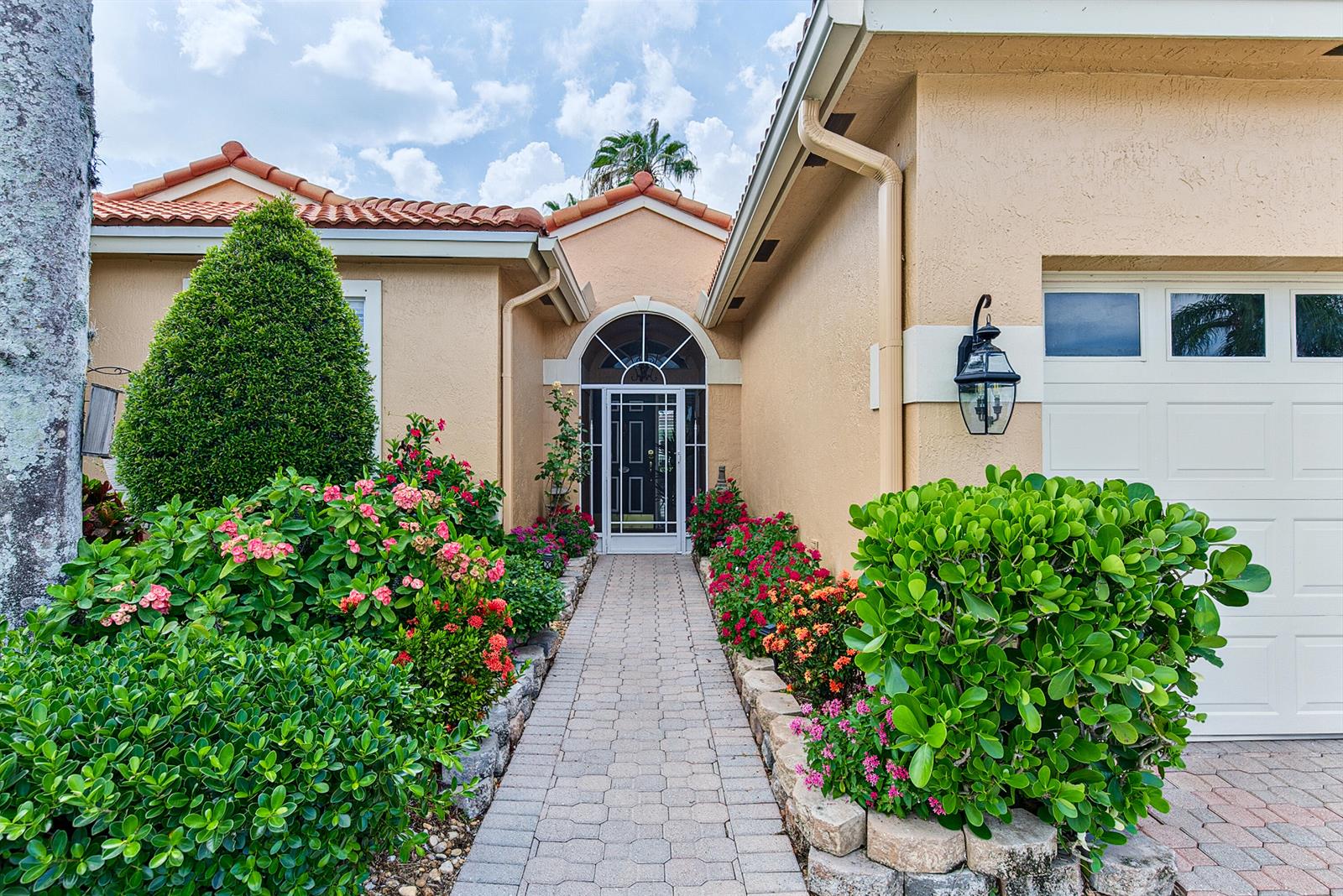 A paved walkway leads to the front entrance of a house with landscaped flower beds — 22011 Palm Grass Drive, Boca Raton FL 33428, BOCA RATON, FL