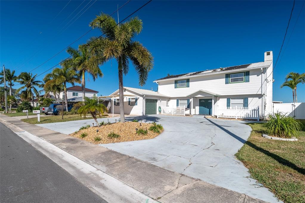 A two-story white house with a large concrete driveway and palm trees in the front — 610 PAULA AVENUE, MERRITT ISLAND, FL