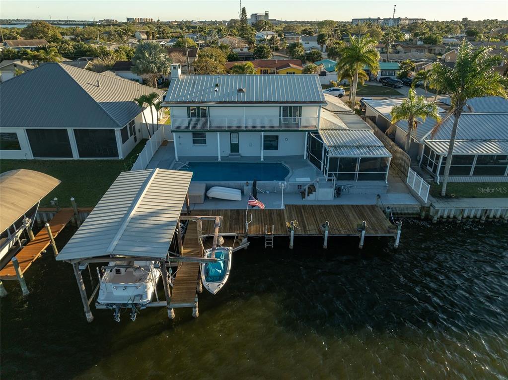 An aerial view shows a two-story waterfront house with a pool, dock, and boat lift — 610 PAULA AVENUE, MERRITT ISLAND, FL