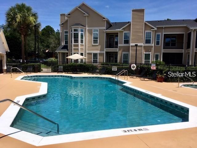 A swimming pool sits in front of a multi-story apartment building under a clear sky — 2015 ERVING CIRCLE UNIT 304, OCOEE, FL