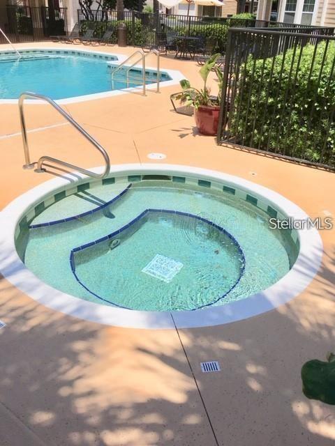A circular hot tub sits on a tan pool deck next to a swimming pool — 2015 ERVING CIRCLE UNIT 304, OCOEE, FL