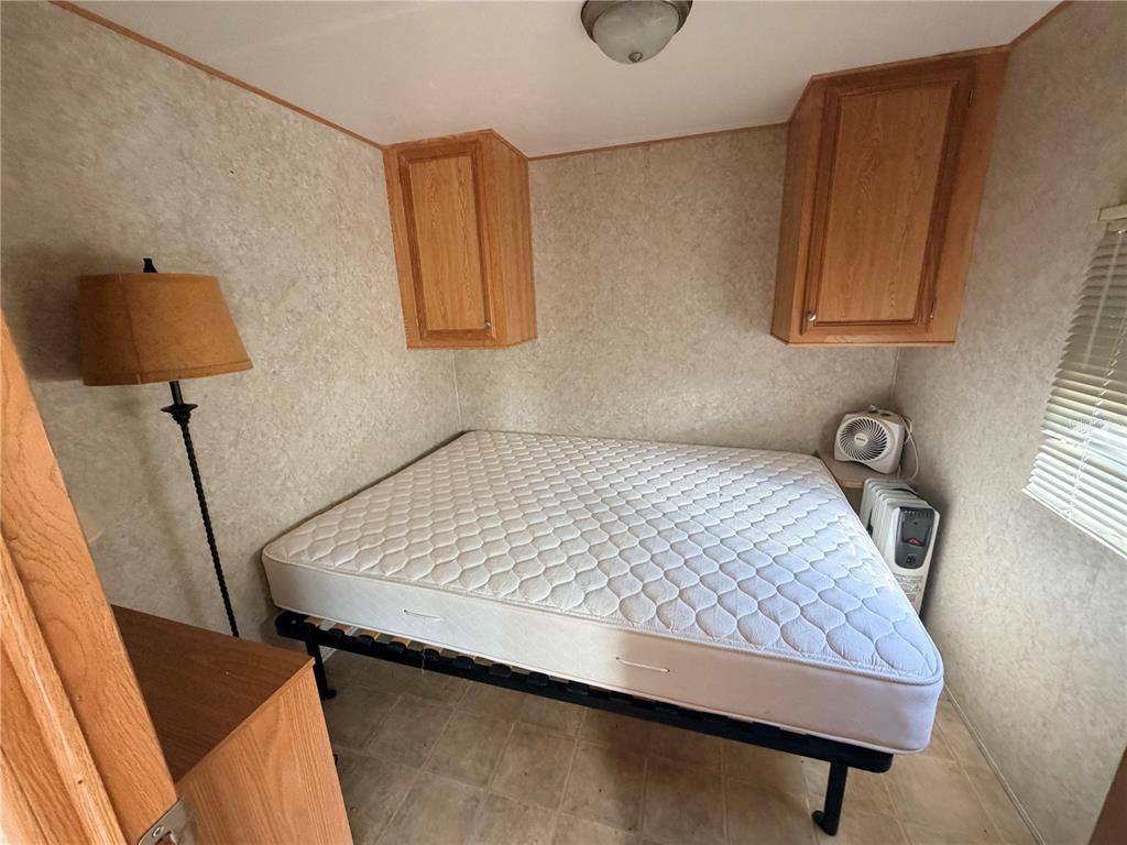 A bedroom features a mattress on a metal frame, wall-mounted cabinets, and a floor lamp — 38212 KINGBIRD WAY, LEESBURG, FL