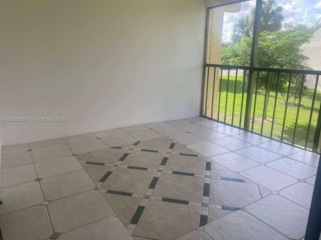 A screened-in balcony features light-colored floor tiles with a decorative central inlay pattern — 220 Lakeview Dr # 203, Weston FL 33326, WESTON, FL