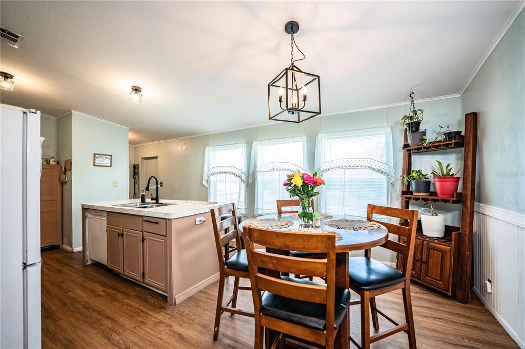 A kitchen and dining area features a central island, wooden furniture, and a hanging light fixture — 487 LINDSEY DRIVE, LAKELAND, FL