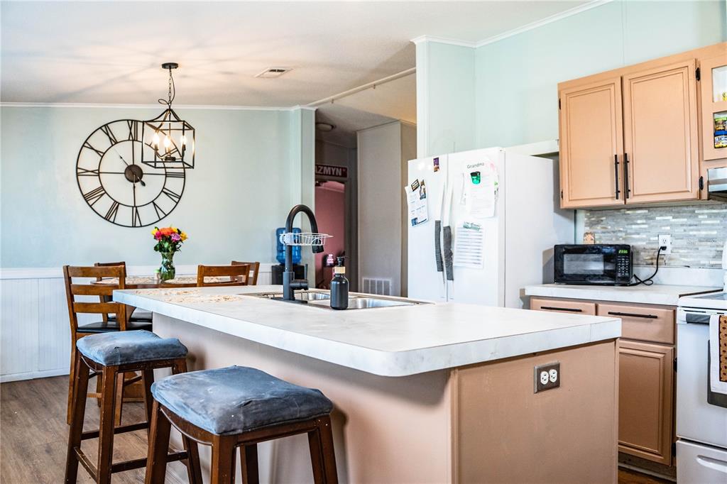 A kitchen features a central island with a sink, light-colored cabinets, and a dining area — 487 LINDSEY DRIVE, LAKELAND, FL