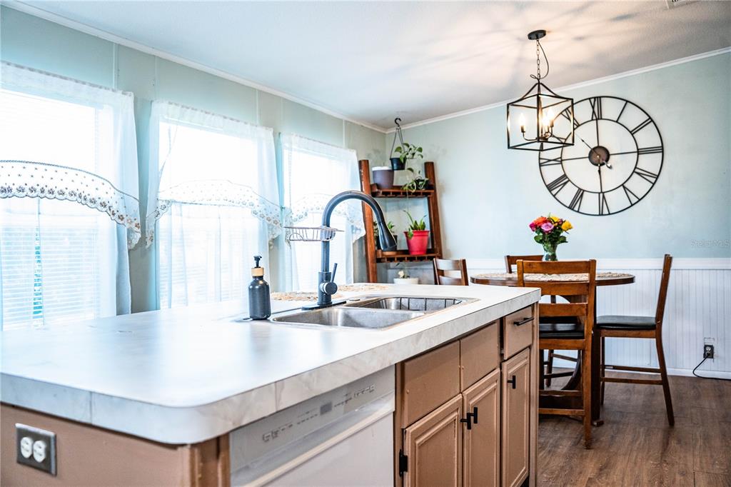 A kitchen island with a sink and dishwasher sits in front of a dining area — 487 LINDSEY DRIVE, LAKELAND, FL
