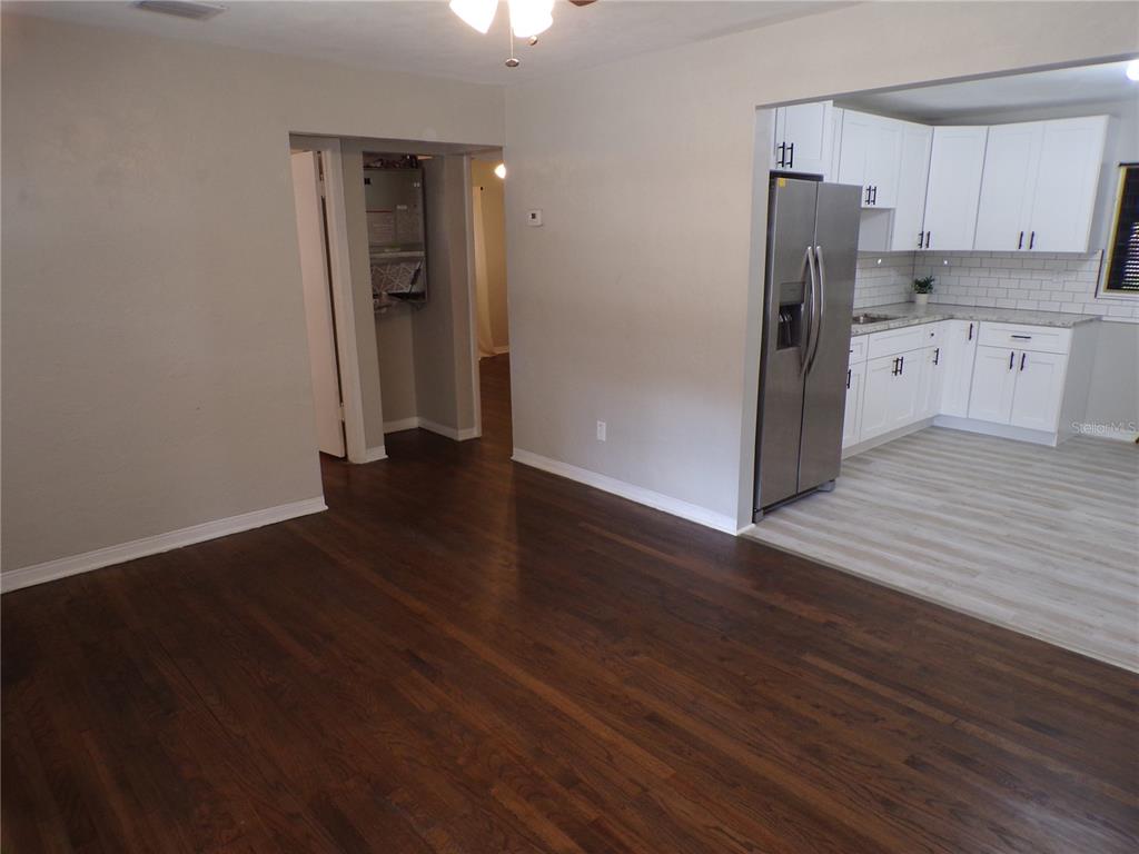 A living room with dark wood floors leads into a kitchen with white cabinets — 4402 73RD STREET N, ST PETERSBURG, FL