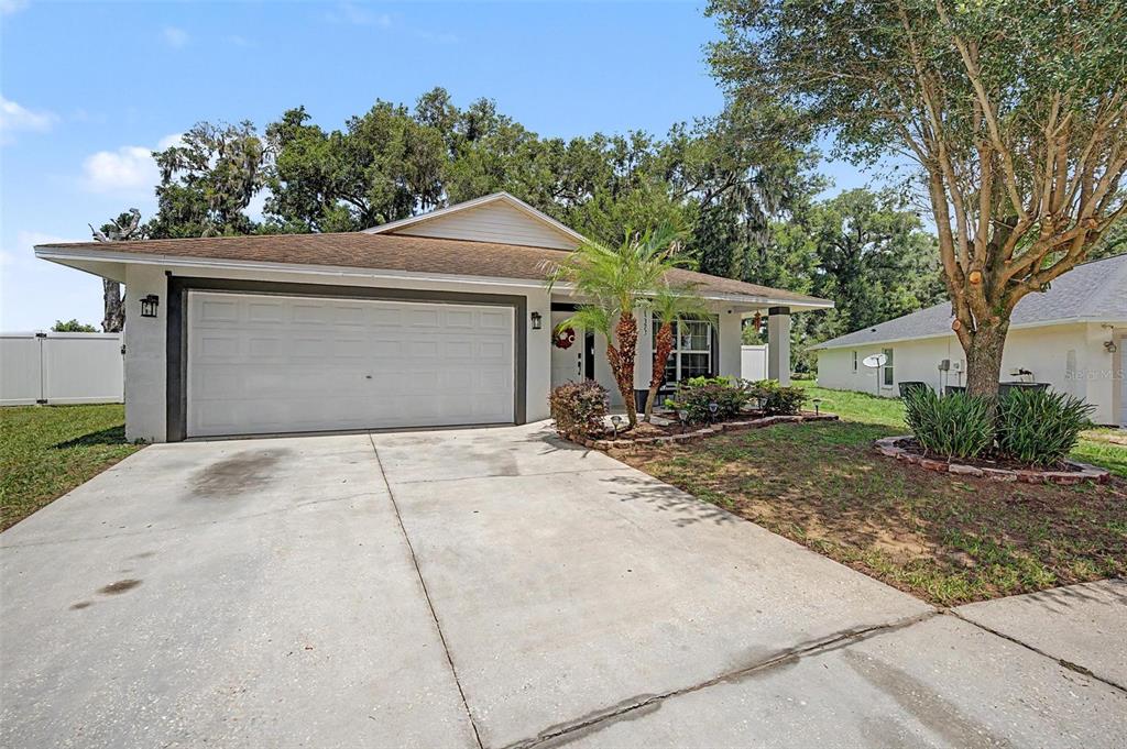 A single-story house with a white exterior, a two-car garage, and a concrete driveway — 15373 CALLISTA LANE, DADE CITY, FL