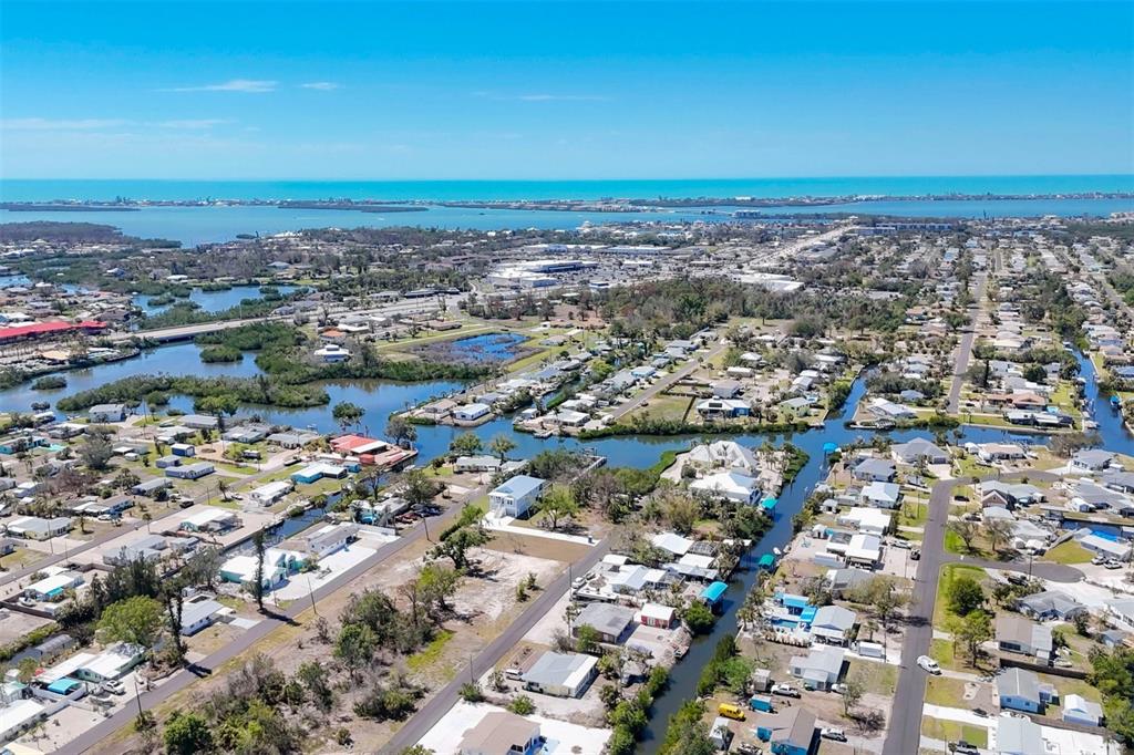 An aerial view shows a residential neighborhood with canals, houses, and the ocean beyond — 1195 ANDREWS STREET, ENGLEWOOD, FL