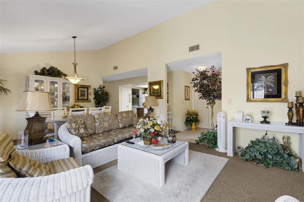 A living room features white wicker furniture, a glass-topped coffee table, and beige walls — 4223 OAK LOOP UNIT 49, MULBERRY, FL