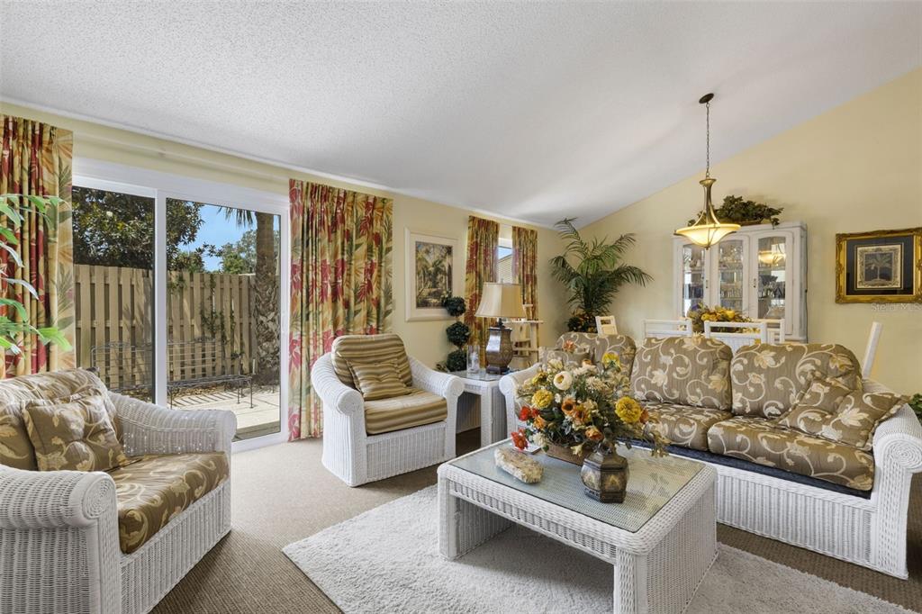 A living room with white wicker furniture, a glass-top coffee table, and sliding glass doors — 4223 OAK LOOP UNIT 49, MULBERRY, FL