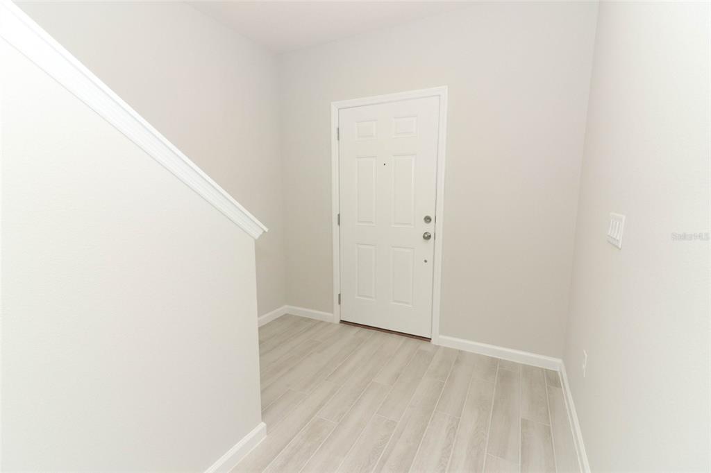 An entryway features light-colored wood-look tile flooring, white walls, and a white front door — 3031 PILOT HOUSE PLACE, OVIEDO, FL