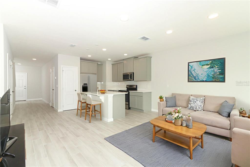 An open-concept living room and kitchen featuring light gray cabinets, a kitchen island, and tile flooring — 3031 PILOT HOUSE PLACE, OVIEDO, FL