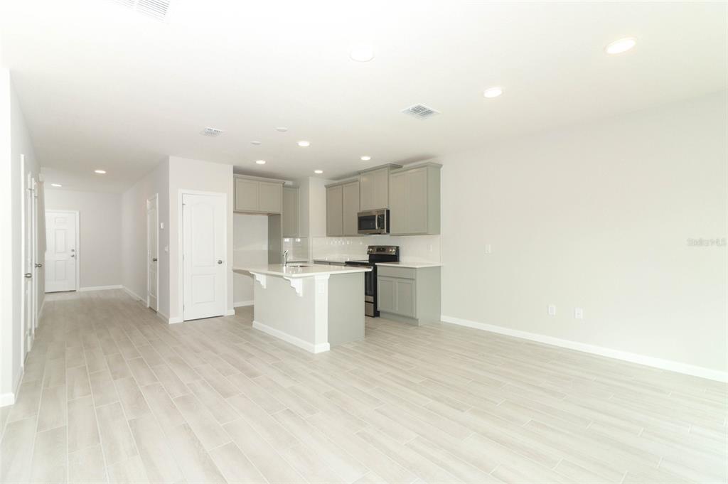 A modern kitchen with gray cabinets and a white island opens into a living area — 3031 PILOT HOUSE PLACE, OVIEDO, FL