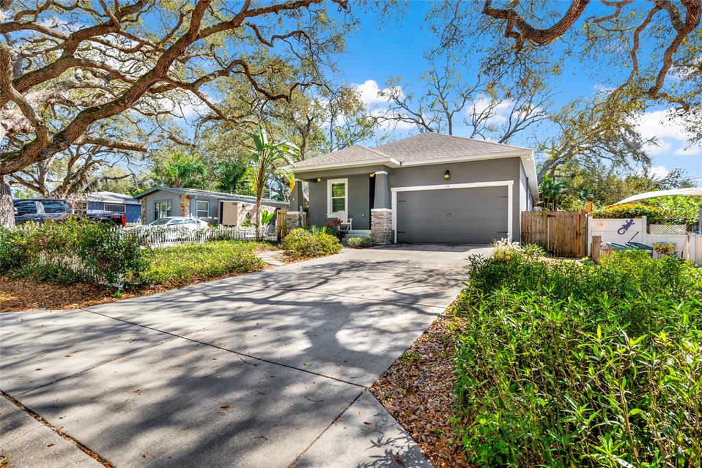 A gray single-story house with a concrete driveway and large oak trees in the yard — 131 PENNSYLVANIA AVENUE, PALM HARBOR, FL