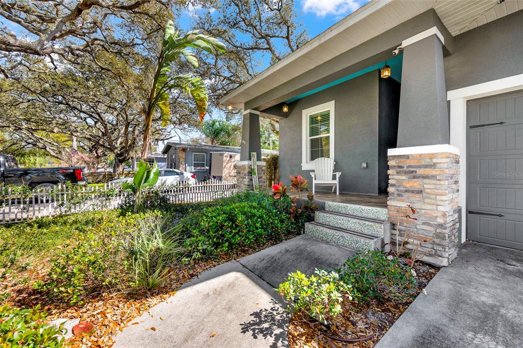 A gray house with a stone-accented porch, a white chair, and a concrete walkway — 131 PENNSYLVANIA AVENUE, PALM HARBOR, FL