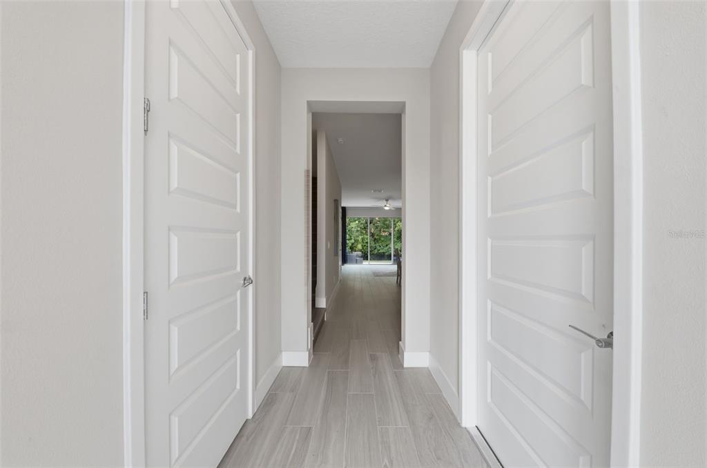 A hallway with light-colored tile flooring leads to an open living area with glass doors — 1216 ROYAL VIEW TERRACE, KISSIMMEE, FL