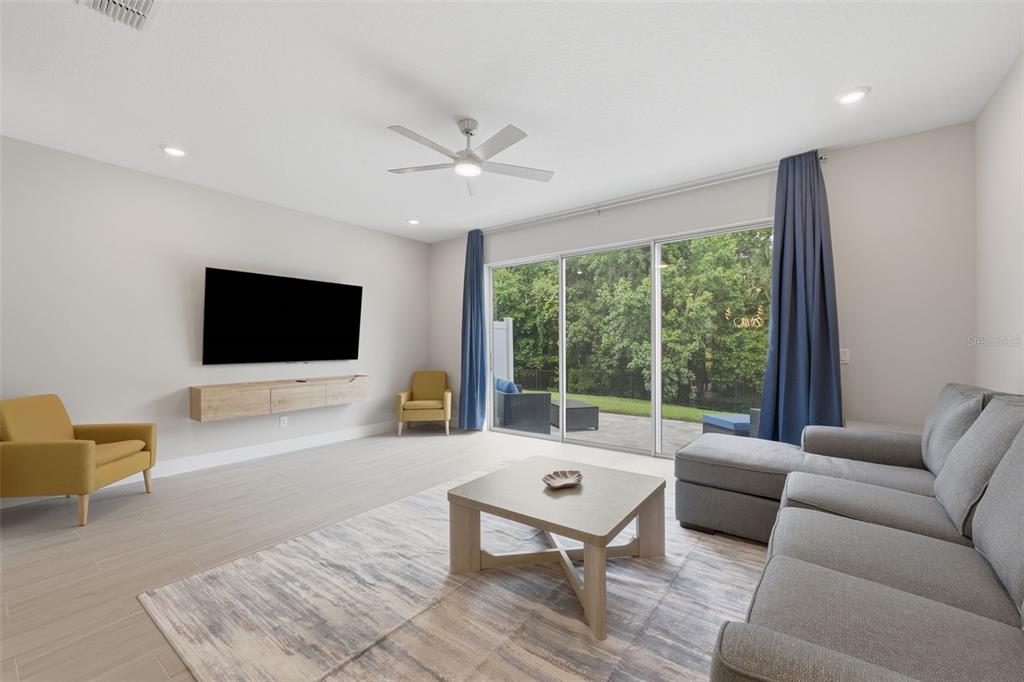 A living room features a grey sectional sofa, yellow armchairs, and a sliding glass door — 1216 ROYAL VIEW TERRACE, KISSIMMEE, FL